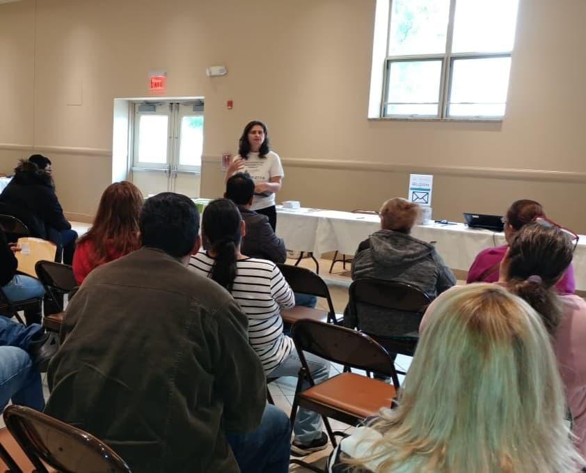 A FLAP staff member speaks to workers seated in a community hall.