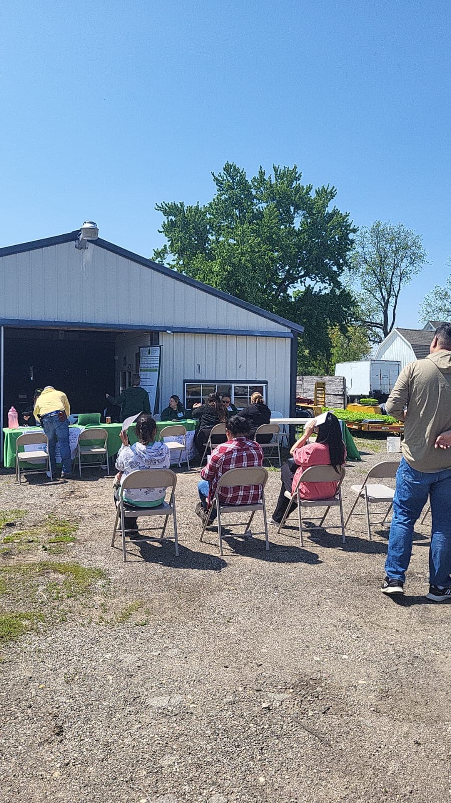 Farmworkers attend a FLAP information session held in the yard of a farm.