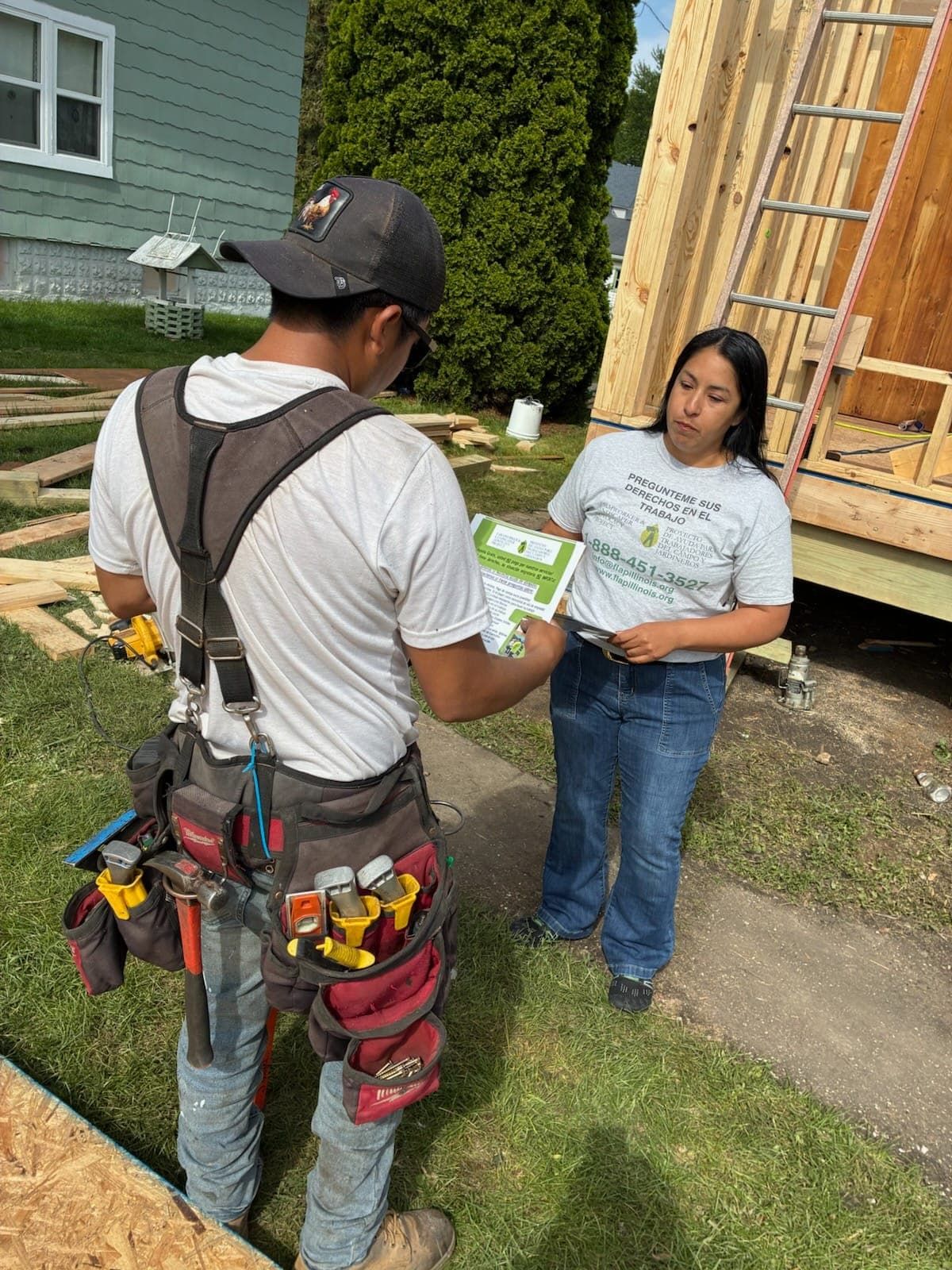 A FLAP outreach worker gives know-your-rights materials to a carpenter at a construction site.