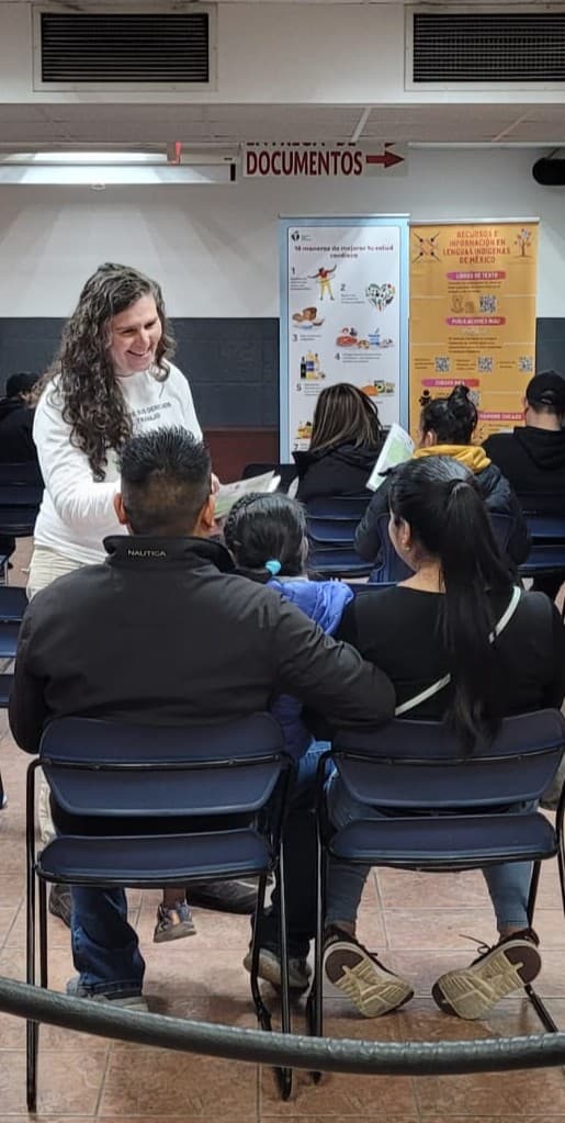 A FLAP staff member hands out materials to families waiting in a consulate waiting room.