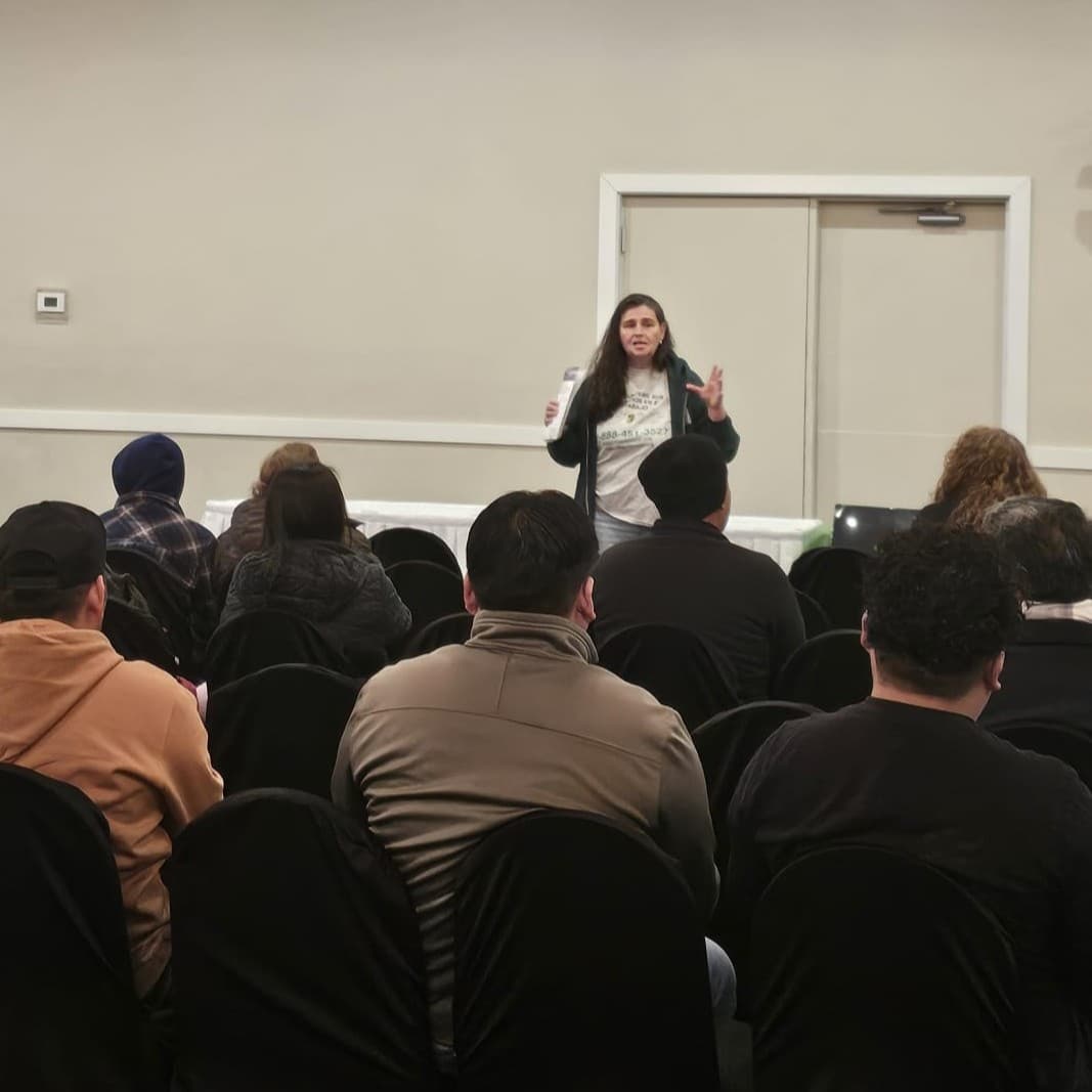 A FLAP staff member speaks to a full room of workers at an evening presentation.