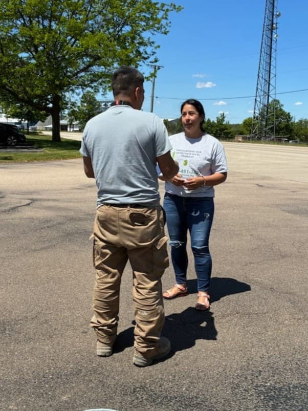 A FLAP outreach worker speaks with a worker in a parking lot during a site visit.