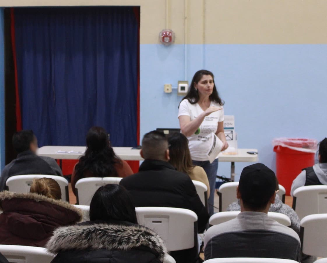 A FLAP attorney presents to workers seated in a community center hall.